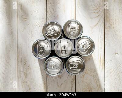 Seven silver metal cans of beer or cold drink over a white wood table on a sunny day. Drinking on the go beverages in aluminum cans with pull tabs. Stock Photo