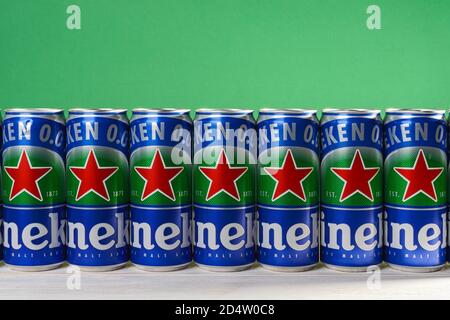 Varna, Bulgaria, October 09, 2020. Row of Heineken 0.0 beer cans with red star on a white wood table against green wall. Nonalcoholic malt lager. Stock Photo
