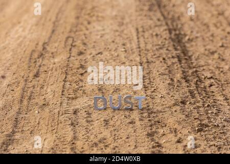 the word dust standing on dusty road surface in linear perspective Stock Photo