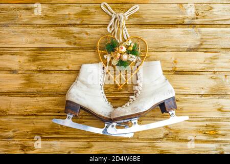 Vintage ice skates for figure skating with fir tree branch and heart with decorations hanging on rustic background. Christmas decoration. Stock Photo