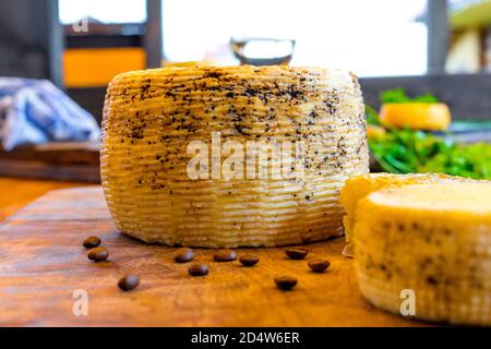 Heads of homemade cheese and coffee beans on a wooden cutting board. Coffee cheese. Homemade cheese with ground coffee. The honey in the comb. Stock Photo