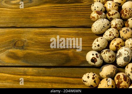 Group of quail eggs. On a brown wooden table made of old grunge planks. Close-up, space for text. Stock Photo