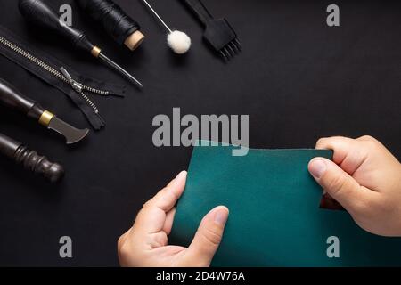 Leather Craftsman holding green leather sample and tool kit for handcraft wallets. Stock Photo