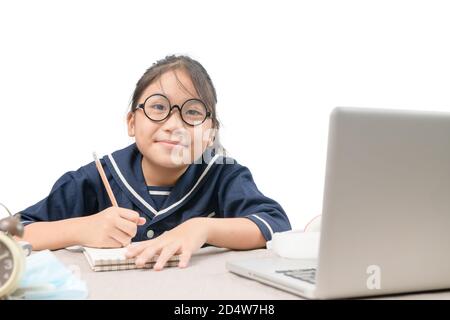 Happy student learning online with laptop and taking notes in a notepad doing homework looking at camera isolated on white background, education and n Stock Photo