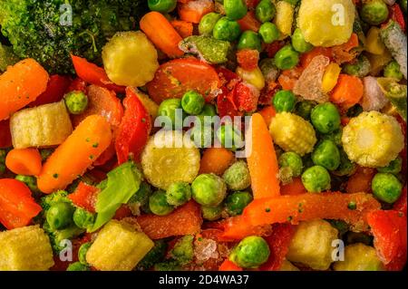 Food background from a mixture of frozen vegetables corn, red pepper, peas, carrots, broccoli, tomatoes, selective focus close up Stock Photo
