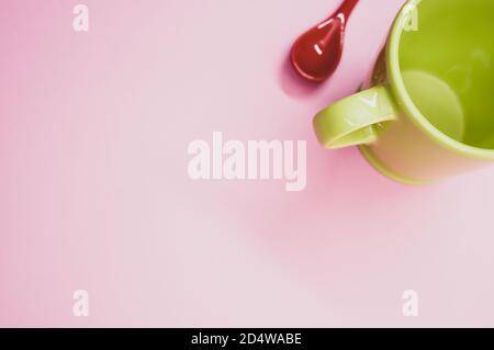 Red ceramic spoon and a light green mug on a light pink background Stock Photo