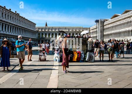 New normal tourism at Piazza San Marco (St. Mark's Square), Venice, Italy, during the coronavirus pandemic with tourists wearing face masks. Stock Photo