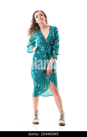 Confident young woman with cocked head posing with hand on hip in floral dress. Full body portrait isolated on white background Stock Photo