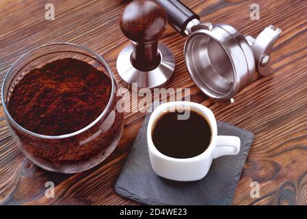 coffee in a cup on a stone stand, glass jar with coffee and coffee accessories tempera and a horn for a coffee machine, wooden natural background, tin Stock Photo