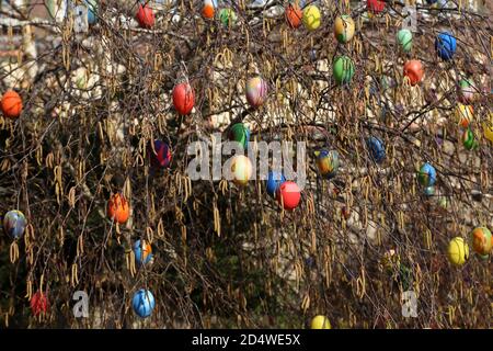 Closeup of decorative Easter eggs hanging on a tree near a fountain in the city Stock Photo
