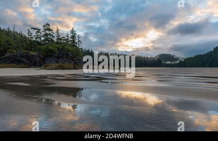 Sun rising behind the clouds on Northern Vancouver Island beach. Stock Photo