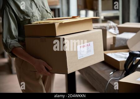 Female worker holding shipping order boxes in warehouse, closeup. Stock Photo