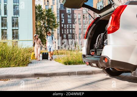 couple gathering for road trip. putting bags to car trunk Stock Photo