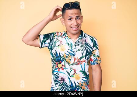 Young handsome latin man wearing summer clothes confuse and wonder about question. uncertain with doubt, thinking with hand on head. pensive concept. Stock Photo