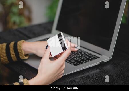 Close up of Female hand holding credit card over laptop for online shopping. Stock Photo