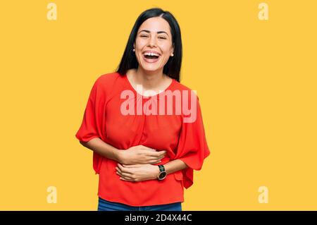 Beautiful young woman wearing casual clothes smiling and laughing hard out loud because funny crazy joke with hands on body.