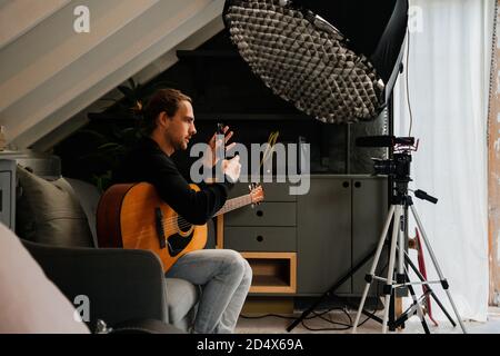 Caucasian male musician recording songs playing guitar in stylish music studio Stock Photo