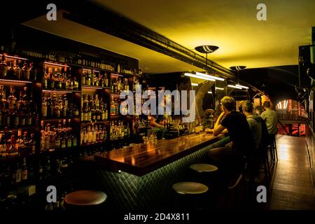 Freiburg, Germany. 09th Oct, 2020. Guests sit at the counter in the One Trick Pony Bar while a bartender stands behind it. The Freiburg bar operators won one of the coveted prizes in the category 'Strategy & Future' at the online Mixology Bar Awards. Credit: Philipp von Ditfurth/dpa/Alamy Live News Stock Photo