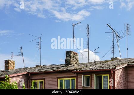 many old analog television antennas of meter and decimeter ranges on the roof with two chimneys Stock Photo