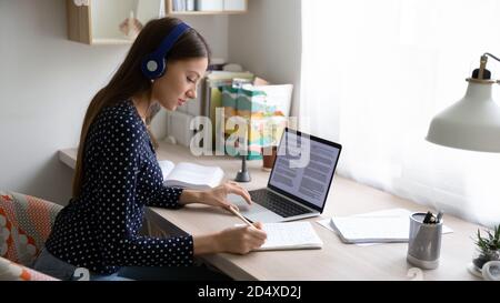 Focused young beautiful caucasian woman studying remotely using laptop. Stock Photo