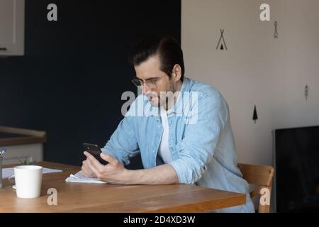 Focused young man using smartphone at home. Stock Photo