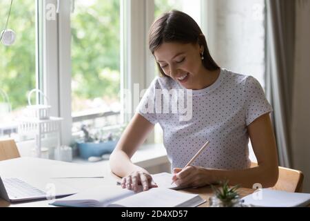 Smiling young european woman studying at home. Stock Photo