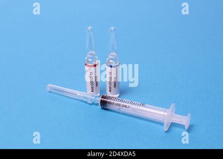 Two medicine ampule with anti covid sars vaccine and syringe on blue background Stock Photo