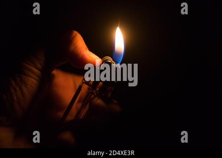 Closeup shot of a hand with lighter igniting sparks on dark background Stock Photo