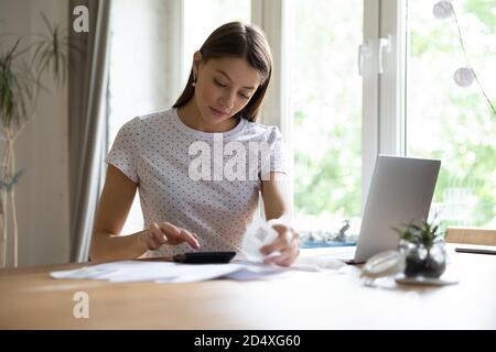 Focused young pretty woman calculating monthly expenses. Stock Photo