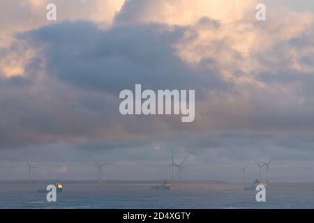 Supply Boats Moored Off the Coast of Aberdeen, Scotland, with Wind Turbines in the Background Stock Photo