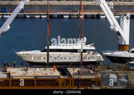 Luxury power boat / yacht being loaded onto a barge in Gibraltar harbour for transport or delivery Stock Photo