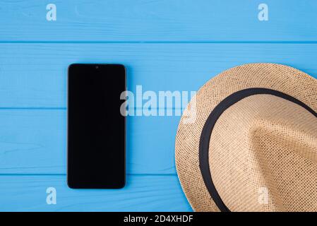 Top above overhead close up photo of straw female hat and black telephone with blank touchscreen isolated over wood bright color background Stock Photo