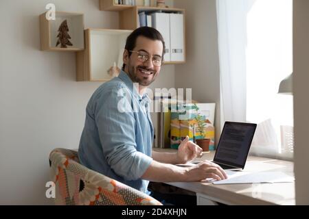 Handsome man in eyeglasses working on computer at home office. Stock Photo