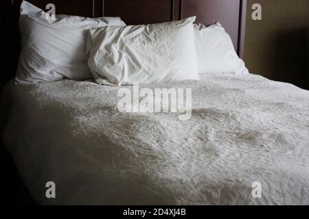 A very lumpy bed with white bedspread and pillows Stock Photo - Alamy