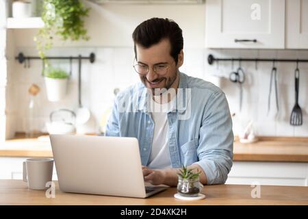 Smiling young guy in glasses enjoying online communication. Stock Photo