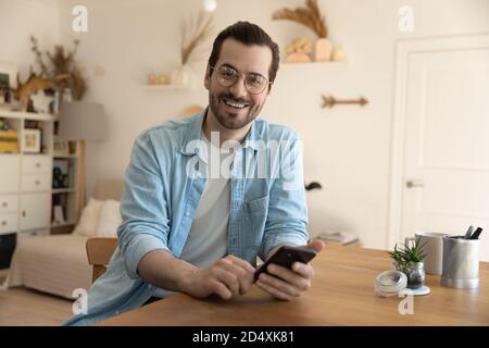 Portrait of happy young man with smartphone in hands. Stock Photo