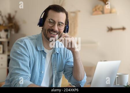 Portrait of smiling young man wearing wireless headphones. Stock Photo