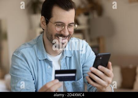 Young smiling man involved in online shopping in mobile app. Stock Photo