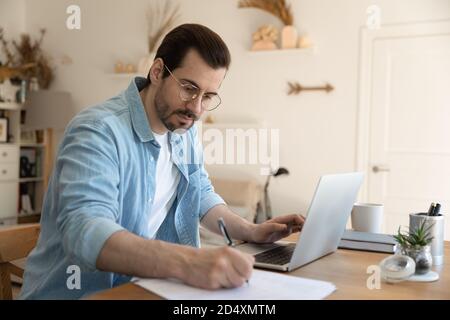 Focused young man watching educational webinar lecture on computer. Stock Photo
