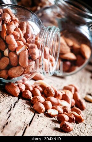 Raw peanuts in a glass jar on the vintage wooden table, selective focus Stock Photo