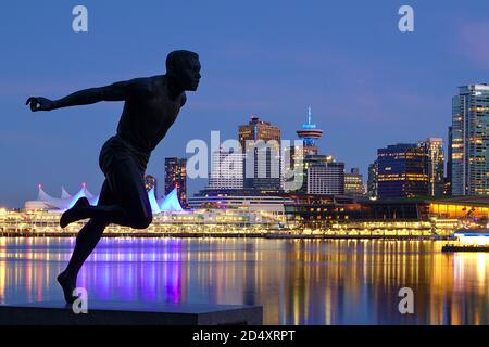 Vancouver, British Columbia - May 14, 2020 - Sprinter statue (Harry Jerome) in Stanley Park with Vancouver Downtown night skyline in the background, b