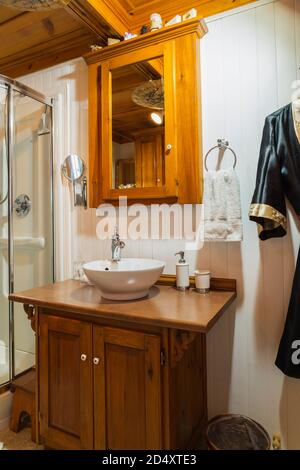 Pine wood medicine cabinet and vanity with bowl sink in bathroom inside an old circa 1840 Canadiana style house. Stock Photo