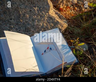 Open blank Journal resting against rock and one the ground, bathed in morning sunlight. Stock Photo