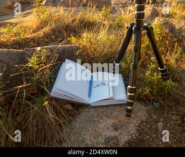 Open blank Journal resting against rock and one the ground, bathed in morning sunlight. Stock Photo