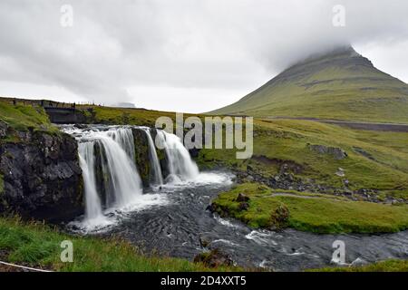 Kirkjufellsfoss and Mount Kirkjufell in Grundarfjörður on the Snaefellsnes Peninsular, Iceland. Top of the mountain is obscured by heavy cloud cover. Stock Photo