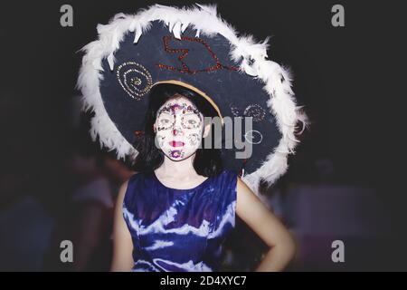 Merida, Mexico - 31 October 2018: Woman dressed as catrina with flower skull make up and big hat with feather for day of the dead 'dia de los muertos' Stock Photo