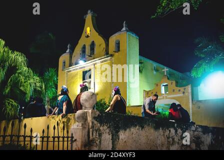 Merida, Mexico - 31 October 2018: Visitors costumed as catrinas at the festival for day of the dead sitting at the colonial church 'Santa Isabel' at n Stock Photo