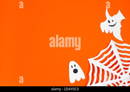 Happy Halloween. Funny paper ghosts for the holiday on orange background. Stock Photo