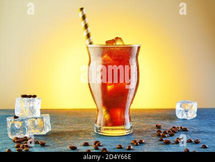 Cold drink or Nitro Coffee drink in a glass with foam, ice and coffee beans. Stock Photo