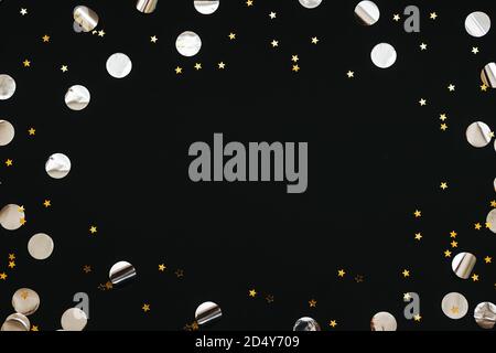 Gold and silver confetti on a black festive background. In the middle there is space for text or copy space. Stock Photo